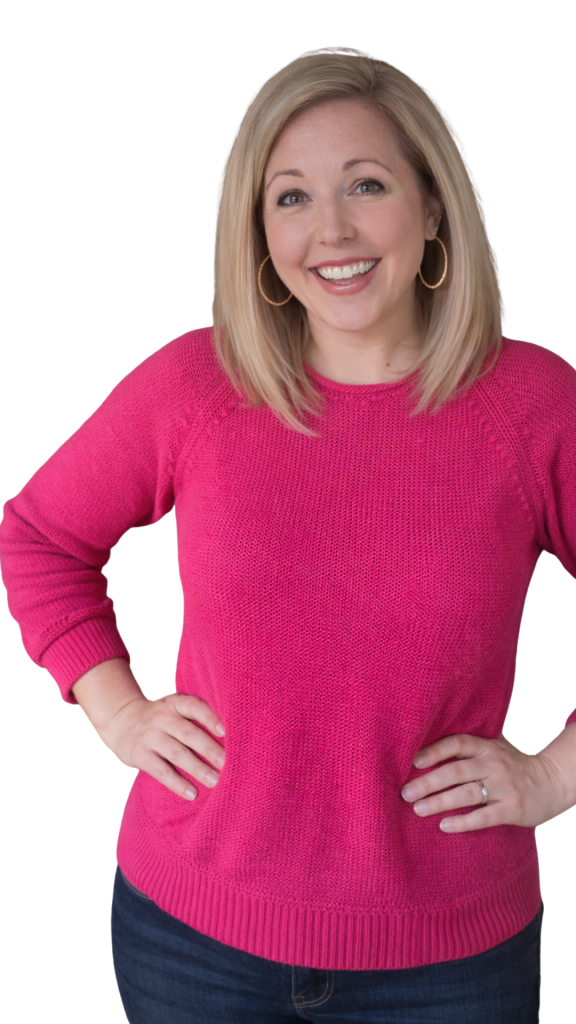 Woman standing confidently with hands on hips, smiling and ready to go in a bright pink sweater.